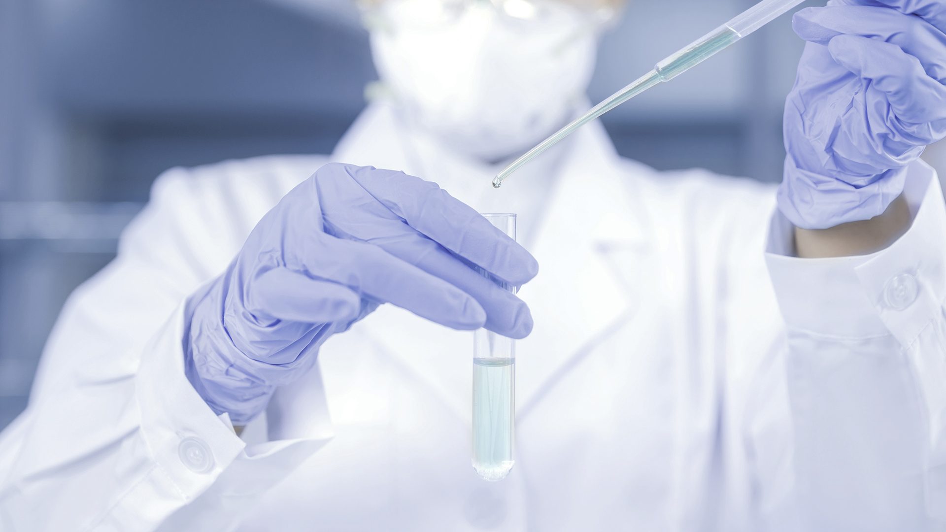 Forsker der dypper væske i et reagensglas.
